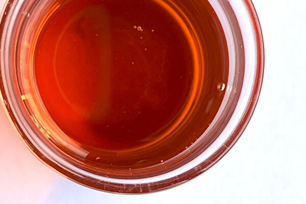 Tekutý obsah vitamínového komplexu A, C, E v sklenenej nádobe.