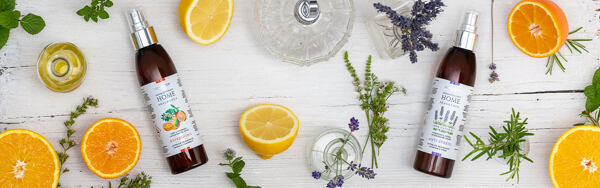 Interiérové spreje Manufaktura s citrusmi, levanduľou a bylinkami na svetlom drevenom stole.