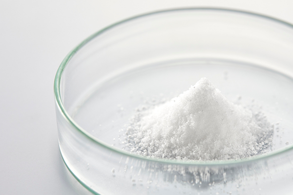 Biely prášok v sklenenej miske na svetlom podklade.