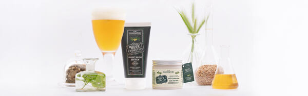 Pivný vlasový balzam a maska s ingredienciami ako chmeľ, pivo a obilie na bielom pozadí.