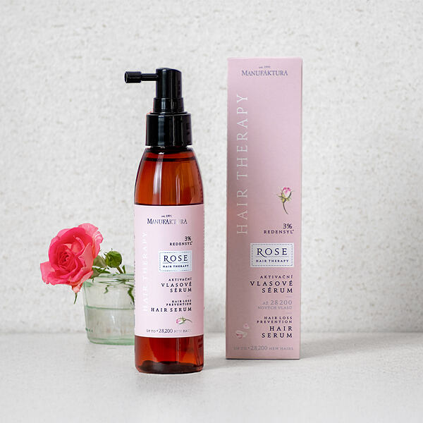 Červená fľaša s ružovým štítkom stojaca vedľa ružovej baliacej škatule s etiketou výrobku