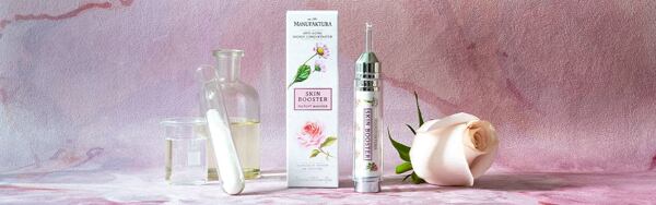Pleťový booster Manufaktura proti vráskam s ružou a sedmokráskou, doplnený ružou a laboratórnymi nádobami na ružovom pozadí.