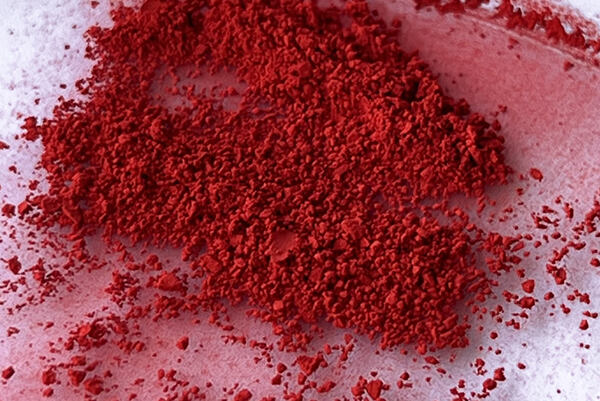 Sypký červený prášok – prírodné farbivo z reďkovky na bielom podklade.