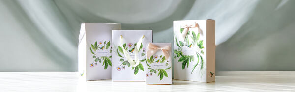 Darčekové tašky a krabičky Manufaktura s rastlinnými ilustráciami a mašľami na svetlom podklade.
