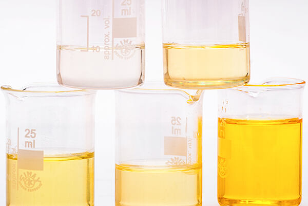 Laboratórne poháre s jojobovým olejom v rôznych odtieňoch.