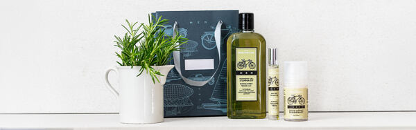 Produkty pánskej kolekcie Manufaktura Men BICYCLE s motívom bicykla, doplnené rozmarínom a darčekovou taškou na svetlom pozadí.