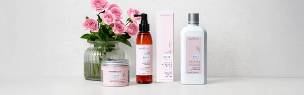 Sada ružovej vlasovej kozmetiky proti starnutiu s ružami na svetlom pozadí.