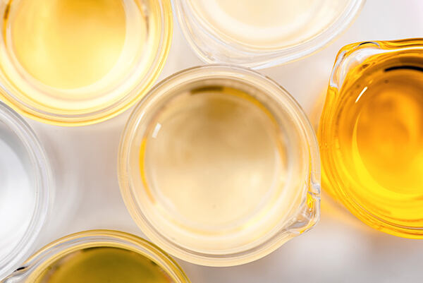 Číry mandľový olej v sklenenej laboratórnej miske medzi ďalšími rastlinnými olejmi.