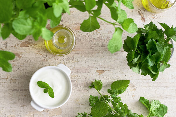 Čerstvá medovka, poháre s olejom a miska s krémom na drevenom stole.