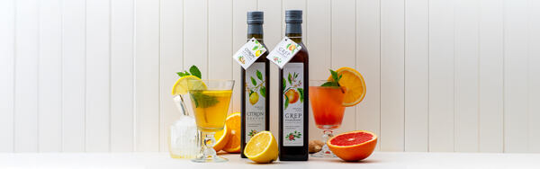 Citrusové sirupy Manufaktura s nápojmi, čerstvým ovocím a mätou na bielom pozadí.