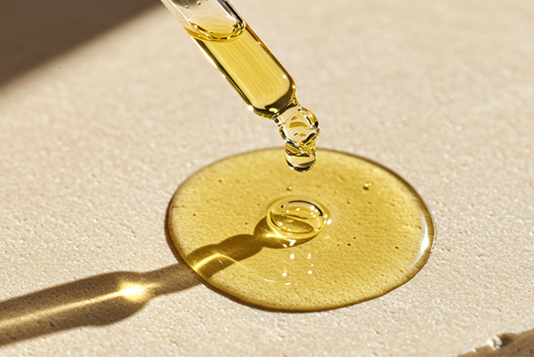 Kvapka žltého séra s pipetou na béžovom podklade.